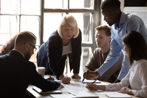 Older leader help diverse team in paperwork analysis at briefing