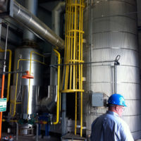 employee with a hard hat stands in front of thermal fluid heater equipment